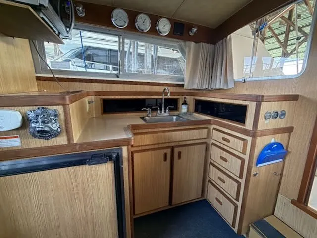 Slide: The Image of 1984 Bertram 30 yacht interior with kitchen and wood paneling. - 10