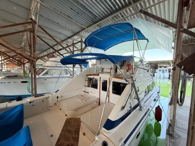 Slide: The Image of 1984 Bertram 30 boat with blue canopy in marina. - 32