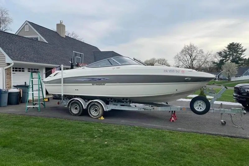 Slide: The Image of 2011 Stingray 235 LR boat on trailer parked in driveway near suburban home. - 2