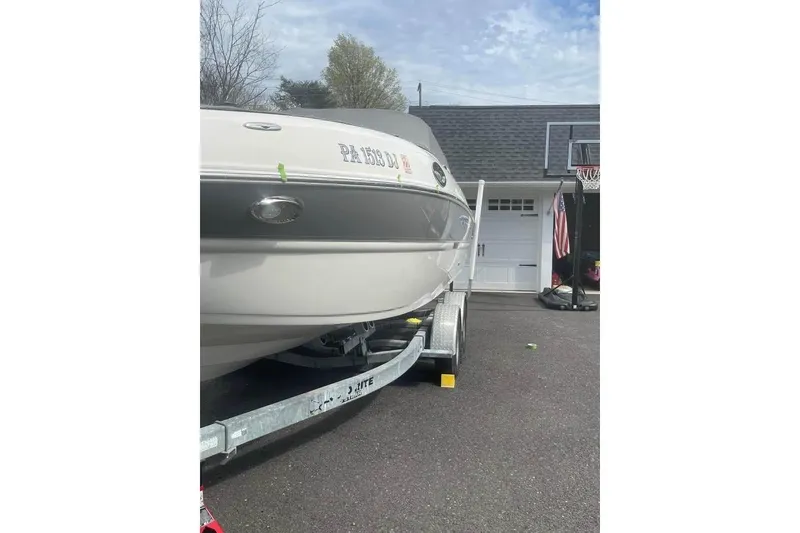 Slide: The Image of 2011 Stingray 235 LR boat on trailer in driveway, near garage and basketball hoop. - 4