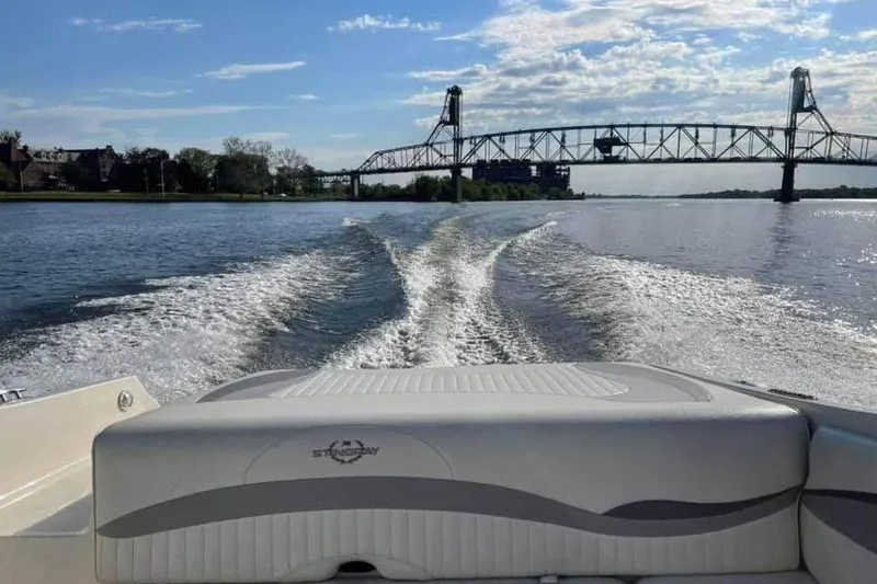 Slide: The Image of 2011 Stingray 235 LR boat cruising on a river with a bridge in the background. - 5