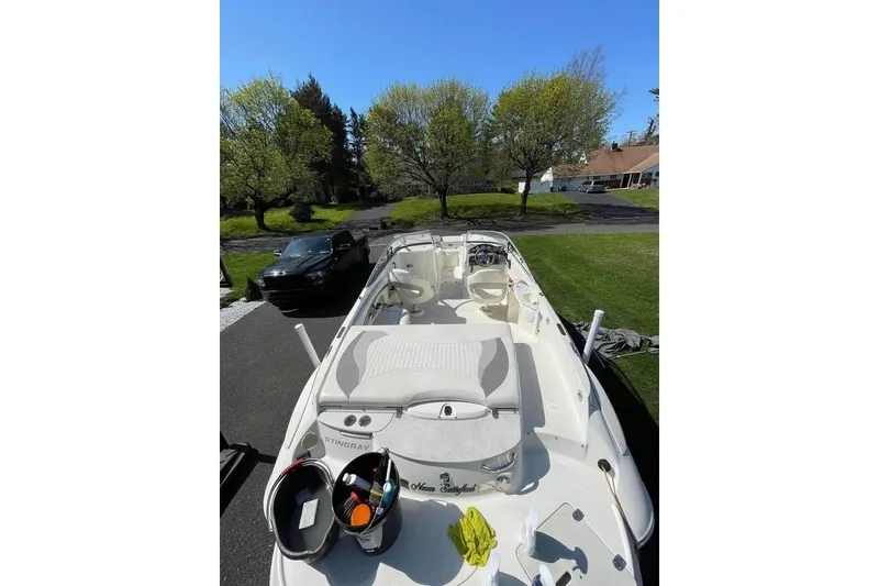 Slide: The Image of 2011 Stingray 235 LR boat on driveway, surrounded by trees and a parked car. - 8