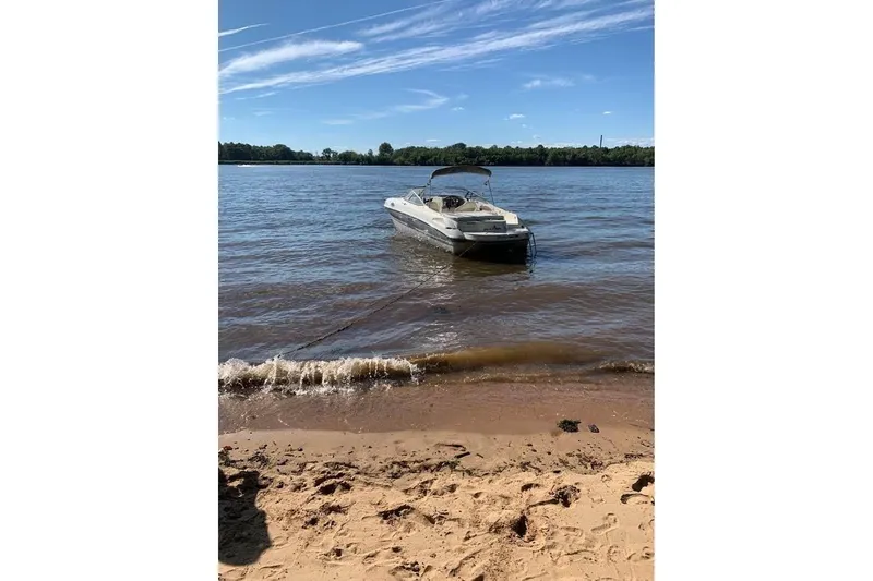 Slide: The Image of 2011 Stingray 235 LR boat anchored near sandy beach under clear blue sky. - 9