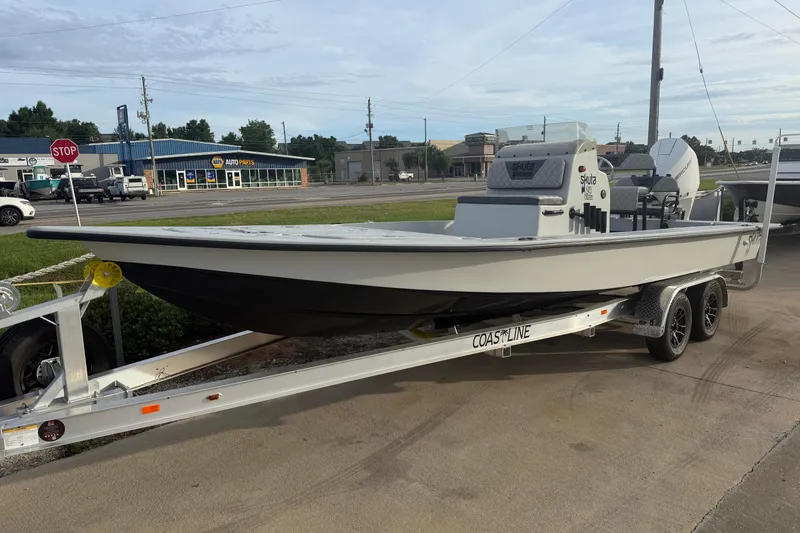 Slide: The Image of 2026 Skuta Vista 24 boat on trailer in parking lot near auto parts store. - 2