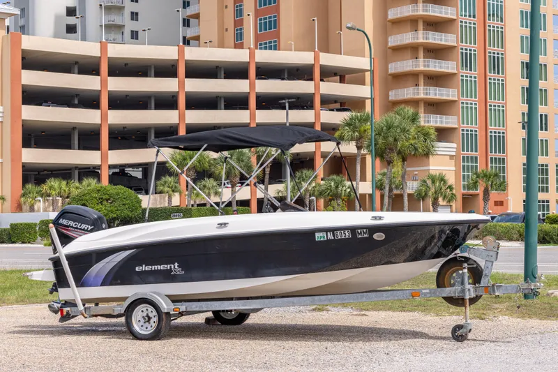 The Image of 2015 Bayliner Element XL boat on trailer, parked near urban buildings. - 0