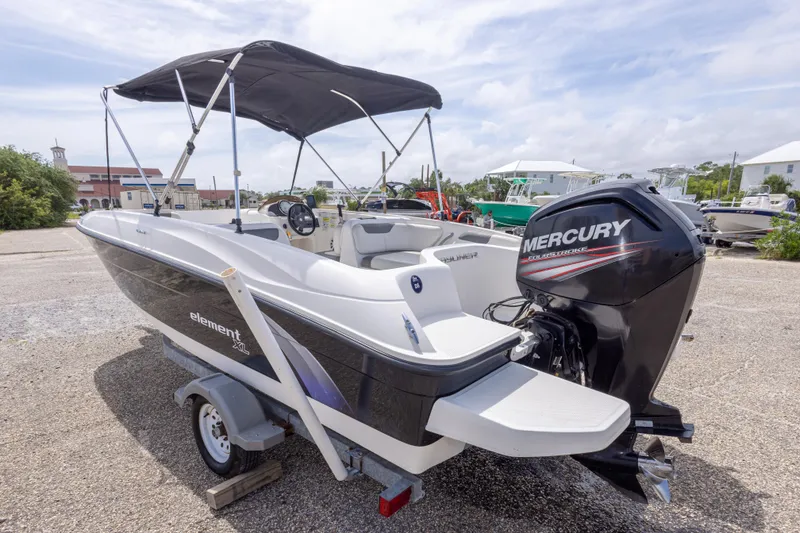 Slide: The Image of 2015 Bayliner Element XL boat with Mercury engine, parked outdoors under a canopy. - 13