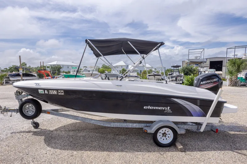 Slide: The Image of 2015 Bayliner Element XL boat on trailer with Mercury outboard motor, parked outdoors. - 14