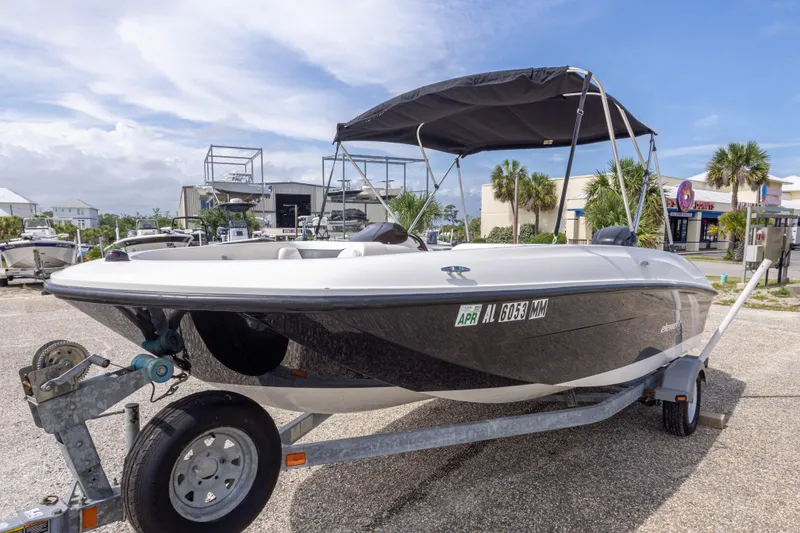 Slide: The Image of 2015 Bayliner Element XL boat on trailer, parked outdoors under a clear sky. - 15