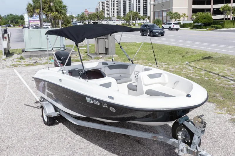 Slide: The Image of 2015 Bayliner Element XL boat on trailer, parked outdoors with canopy. - 2