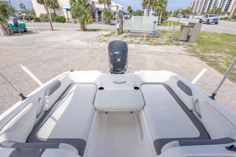 Slide: The Image of 2015 Bayliner Element XL boat interior with seating and motor, parked outdoors. - 21
