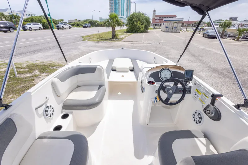 Slide: The Image of 2015 Bayliner Element XL boat interior with seating and steering console, parked near a road. - 23