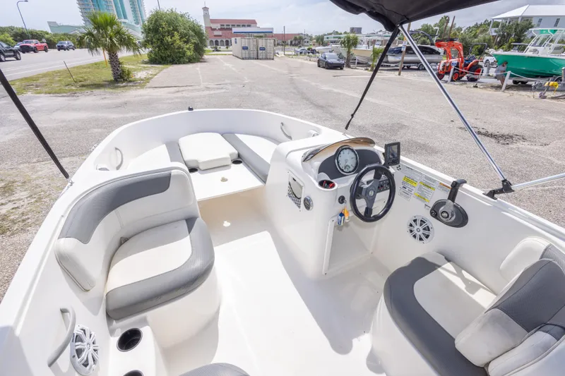 Slide: The Image of 2015 Bayliner Element XL boat interior with seating and steering console, parked near a road. - 24