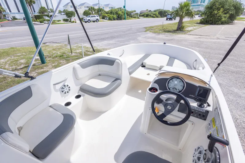 Slide: The Image of 2015 Bayliner Element XL boat interior with seating and steering console, parked near a road. - 25