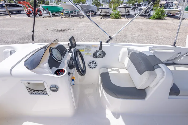 Slide: The Image of 2015 Bayliner Element XL boat interior with steering wheel and seating, parked in a marina. - 29