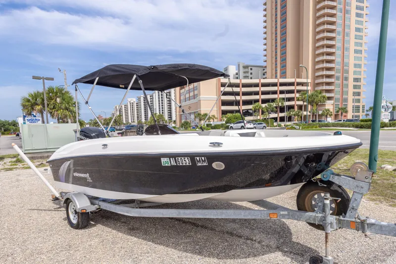 Slide: The Image of 2015 Bayliner Element XL boat on trailer, parked near tall buildings. - 4