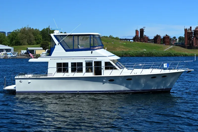 The Image of 1999 McKinna 47 Sedan yacht cruising on a scenic waterway. - 1