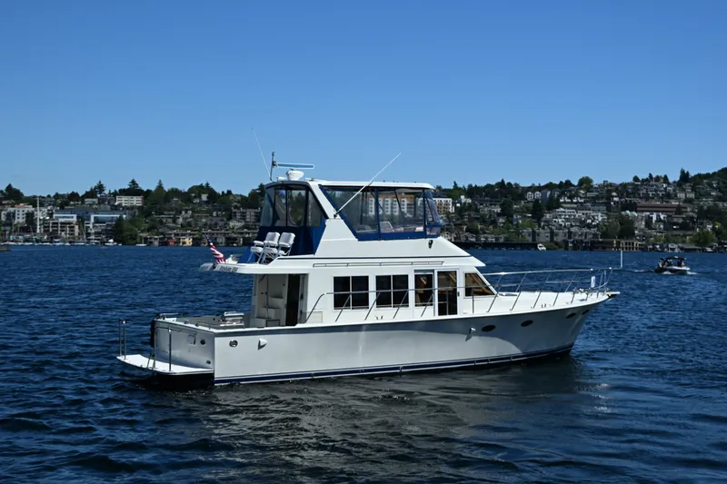 Slide: The Image of 1999 McKinna 47 Sedan yacht cruising on a sunny day in a scenic harbor. - 10