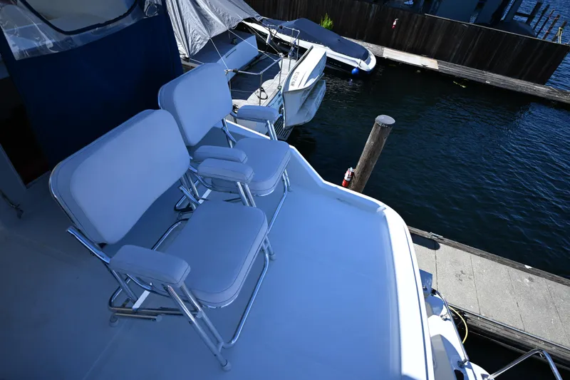 Slide: The Image of 1999 McKinna 47 Sedan yacht with white seating on deck, docked by the water. - 18