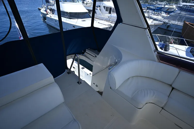 Slide: The Image of Interior view of 1999 McKinna 47 Sedan yacht with white seating and marina backdrop. - 20