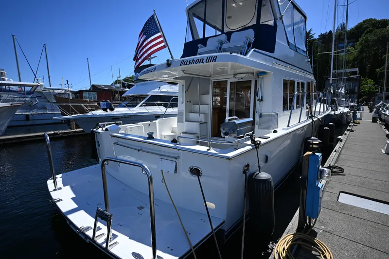 Slide: The Image of 1999 McKinna 47 Sedan yacht docked, featuring American flag and marina setting. - 21