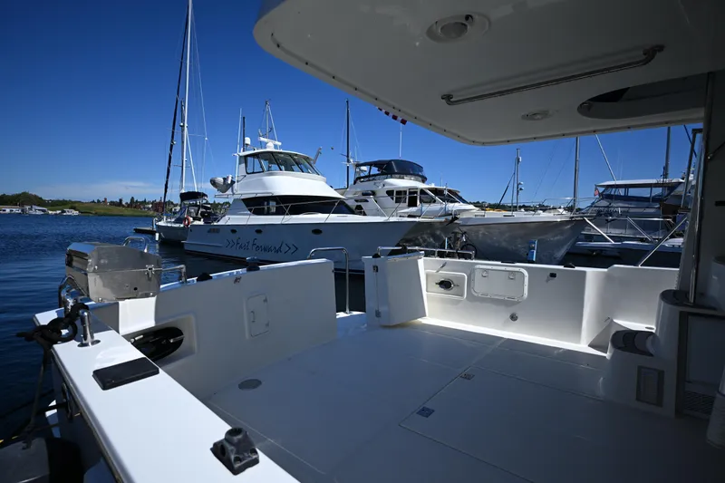 Slide: The Image of 1999 McKinna 47 Sedan yacht docked at marina, surrounded by other boats under clear blue sky. - 22