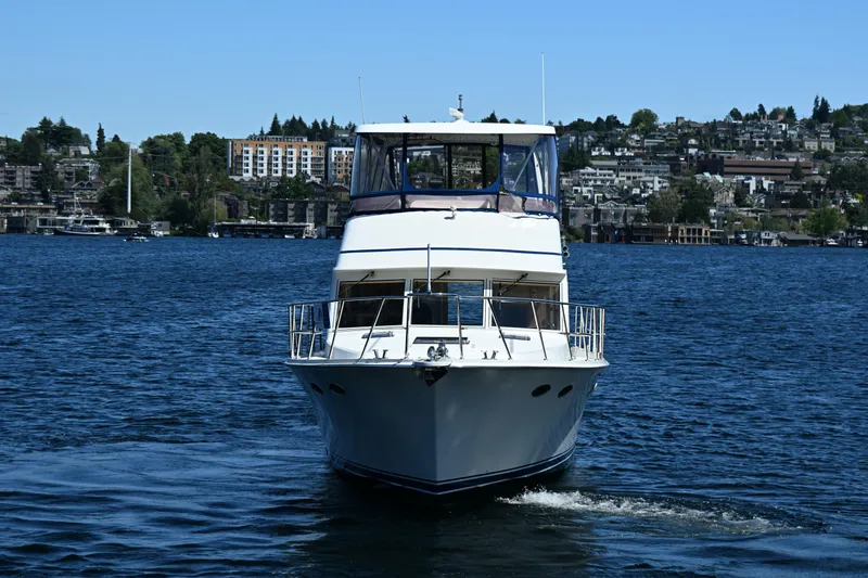 Slide: The Image of 1999 McKinna 47 Sedan yacht cruising on a scenic lake with cityscape background. - 3