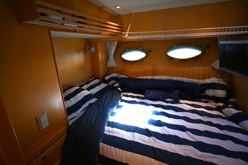 Slide: The Image of Cozy cabin interior of 1999 McKinna 47 Sedan with striped bedding and porthole windows. - 30