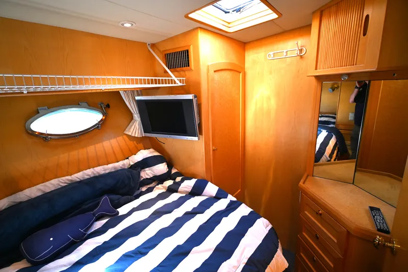 Slide: The Image of Cozy cabin interior of 1999 McKinna 47 Sedan with striped bedding and wooden cabinetry. - 31