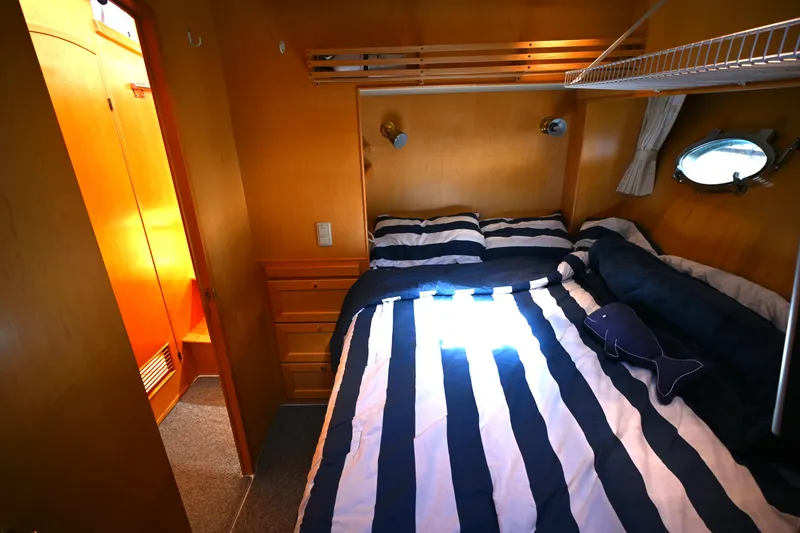 Slide: The Image of Cozy bedroom in 1999 McKinna 47 Sedan yacht with striped bedding and porthole window. - 32