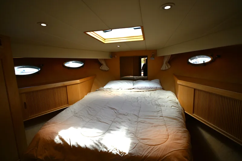 Slide: The Image of Cozy bedroom interior of 1999 McKinna 47 Sedan yacht with skylight and portholes. - 34