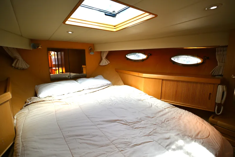 Slide: The Image of Cozy bedroom interior of 1999 McKinna 47 Sedan yacht with skylight and portholes. - 35