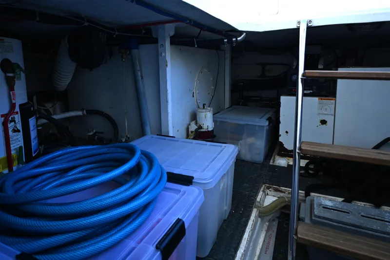 Slide: The Image of Interior storage area of a 1999 McKinna 47 Sedan yacht with plastic containers and coiled hose. - 42
