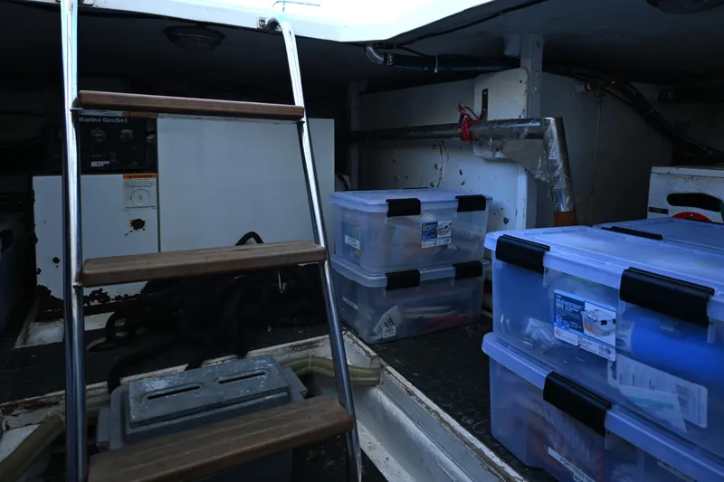 Slide: The Image of Storage area inside a 1999 McKinna 47 Sedan with plastic containers and a ladder. - 43