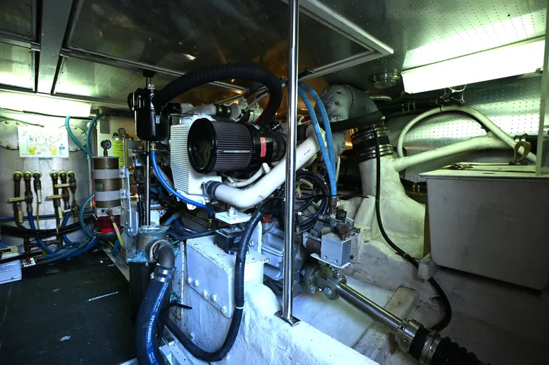 Slide: The Image of Engine room of a 1999 McKinna 47 Sedan yacht, showcasing mechanical components and piping. - 51