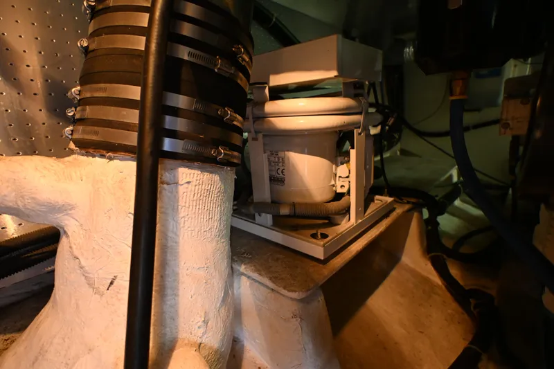 Slide: The Image of Engine room of a 1999 McKinna 47 Sedan yacht, showcasing mechanical components and piping. - 54