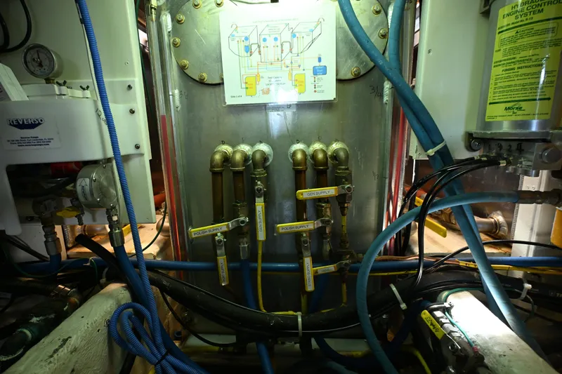 Slide: The Image of Engine room of a 1999 McKinna 47 Sedan with labeled pipes and control systems. - 56