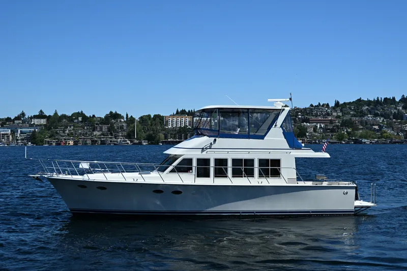 Slide: The Image of 1999 McKinna 47 Sedan yacht cruising on a scenic lake under clear blue skies. - 6