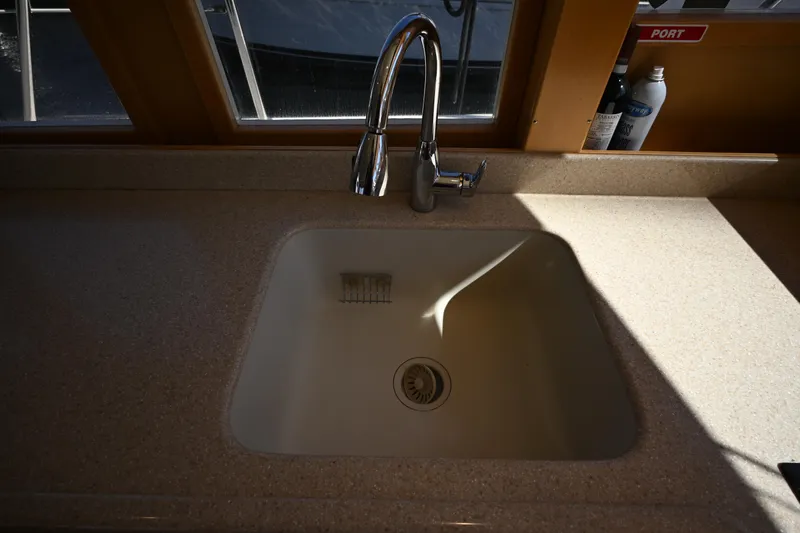 Slide: The Image of Kitchen sink with faucet on 1999 McKinna 47 Sedan yacht, sunlight streaming through window. - 65