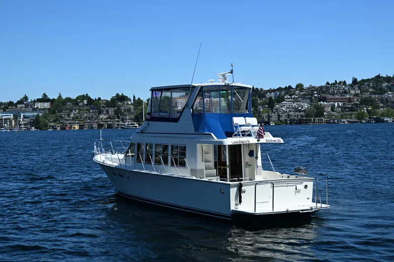 Slide: The Image of 1999 McKinna 47 Sedan yacht cruising on a scenic lake with cityscape background. - 7