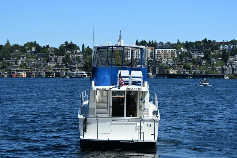 Slide: The Image of 1999 McKinna 47 Sedan yacht on a scenic lake with city backdrop. - 8