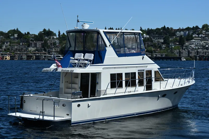 Slide: The Image of 1999 McKinna 47 Sedan yacht on a serene lake with cityscape background. - 9