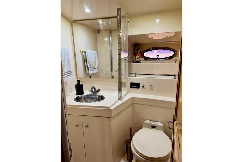 Slide: The Image of 1998 Carver 355 Aft Cabin Motor Yacht bathroom with sink, toilet, and porthole window. - 24