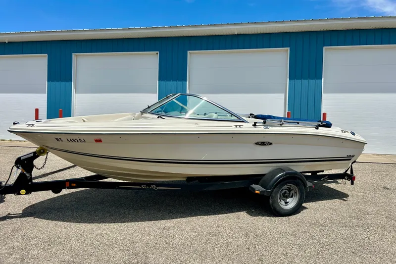 Slide: The Image of 2001 Sea Ray 182 Bow Rider boat on trailer, parked outside blue building. - 2