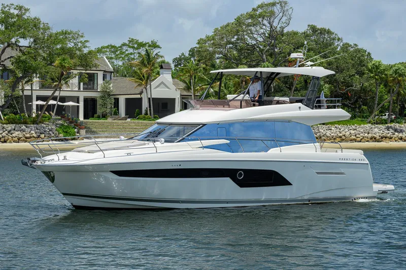 Slide: The Image of Luxury 2021 Prestige 520 yacht cruising near a waterfront estate. - 39