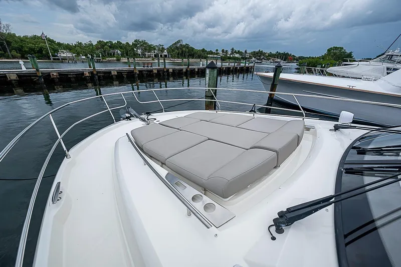 Slide: The Image of Prestige 520 yacht bow with cushioned seating, docked by a scenic waterfront. - 46