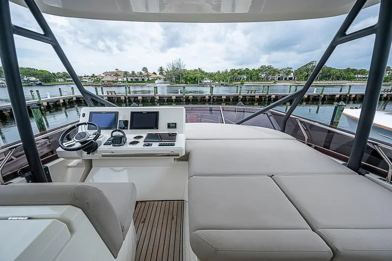 Slide: The Image of Flybridge of 2021 Prestige 520 yacht with helm station and seating, overlooking marina. - 53