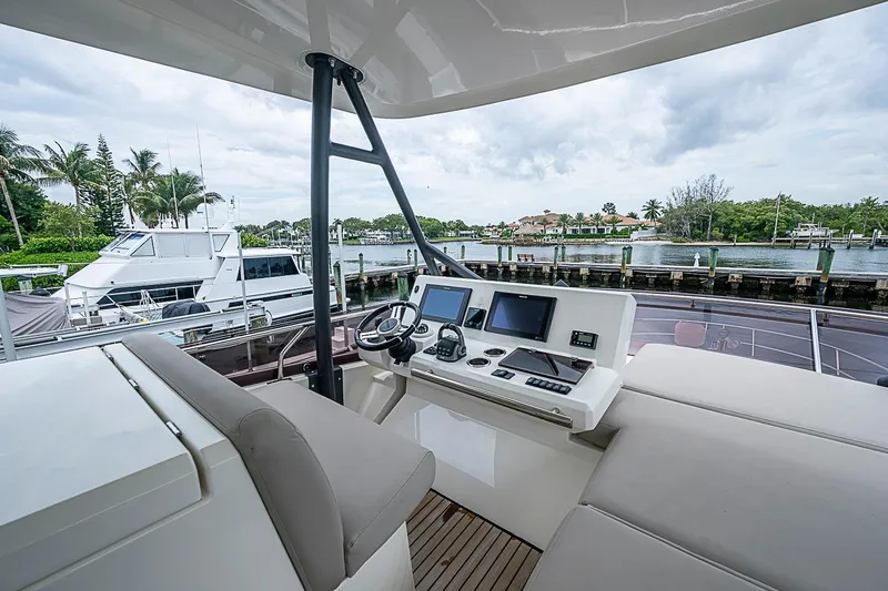 Slide: The Image of Flybridge of 2021 Prestige 520 yacht with modern navigation equipment, docked by waterfront homes. - 54