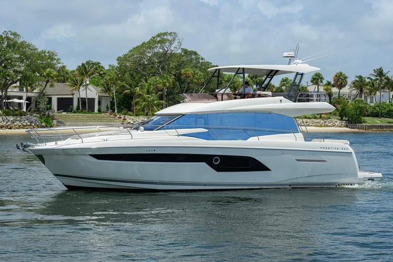 Slide: The Image of Luxury 2021 Prestige 520 yacht cruising near a tropical shoreline with lush greenery. - 39