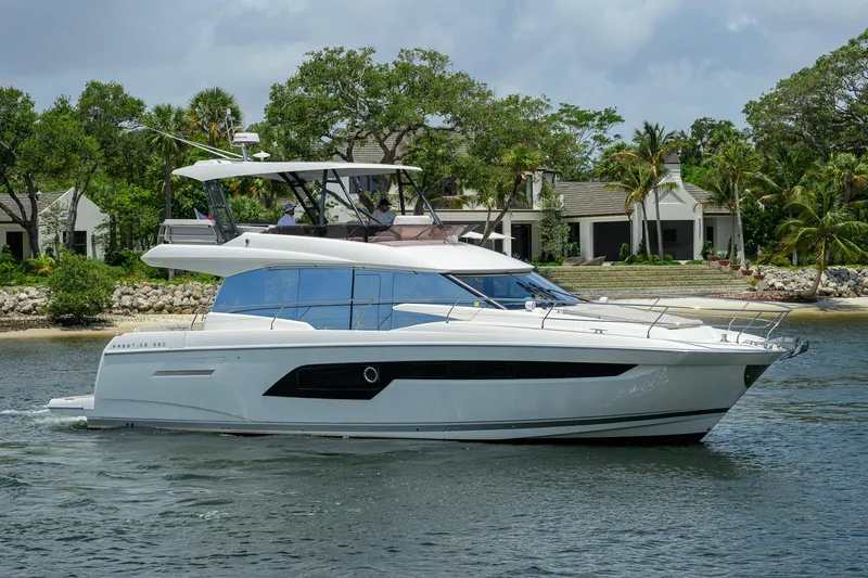Slide: The Image of 2021 Prestige 520 yacht cruising near a tropical shoreline with lush greenery. - 38