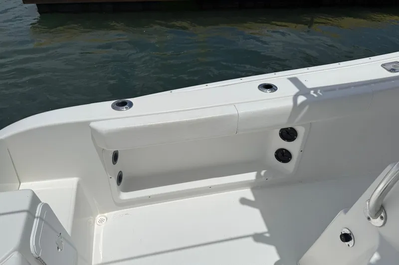 Slide: The Image of 2016 Cape Horn 22 OS boat interior with rod holders and seating, docked by the water. - 24